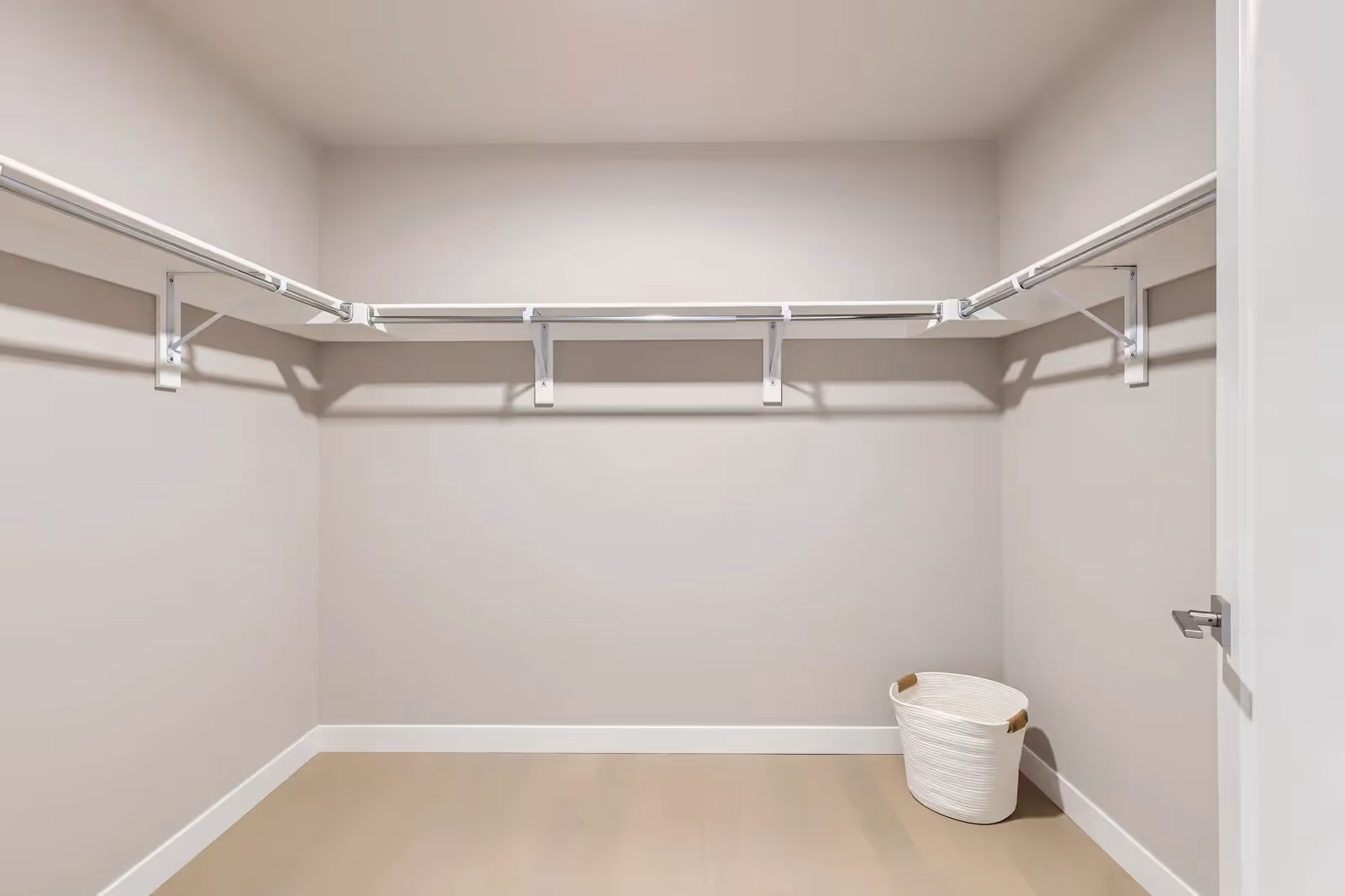 Spacious empty walk-in closet with white wire shelving and light wood flooring in a luxury apartment at The Julian in Sloans Lake, Denver.
