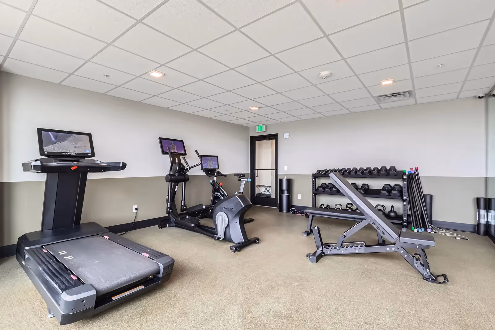 Well-equipped fitness center at The Julian apartments in Sloans Lake, Denver, featuring treadmills, ellipticals, weight benches, and free weights.