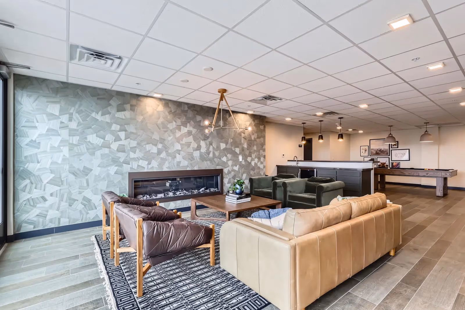 Stylish resident lounge at The Julian apartments in Sloans Lake, Denver, with a modern fireplace, comfortable seating, and an accent wall.
