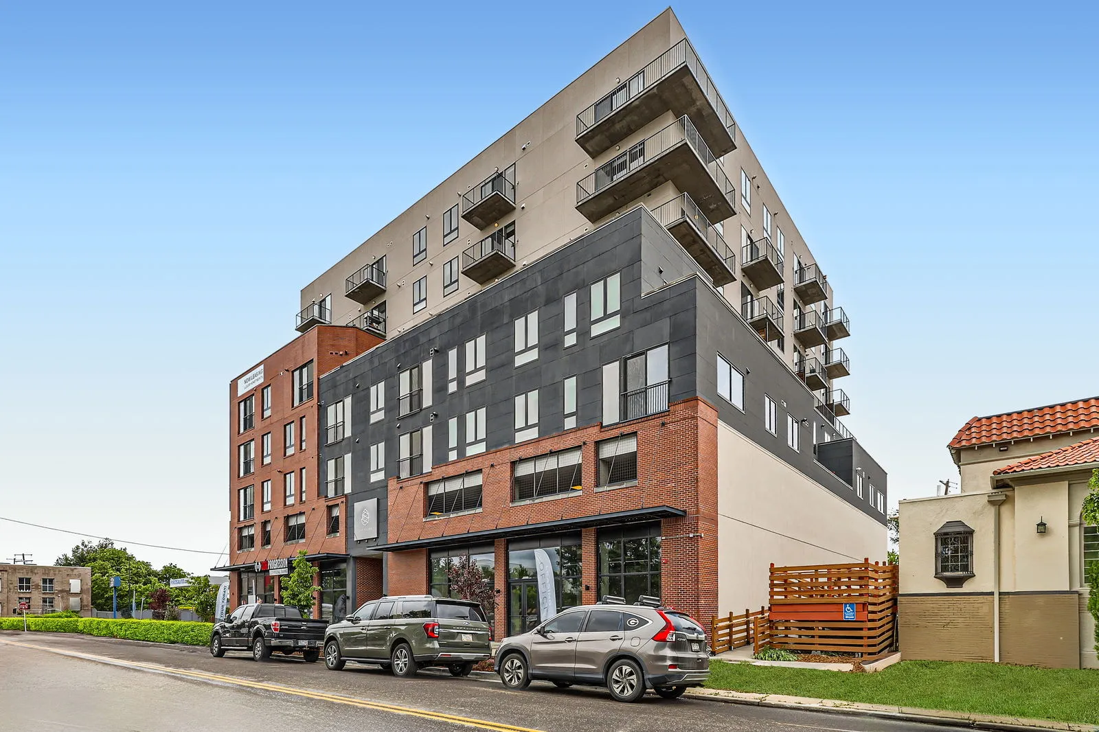 Exterior view of The Julian luxury apartment building in Sloans Lake, Denver, Colorado, on a clear day, showcasing its multi-textured facade and street parking.