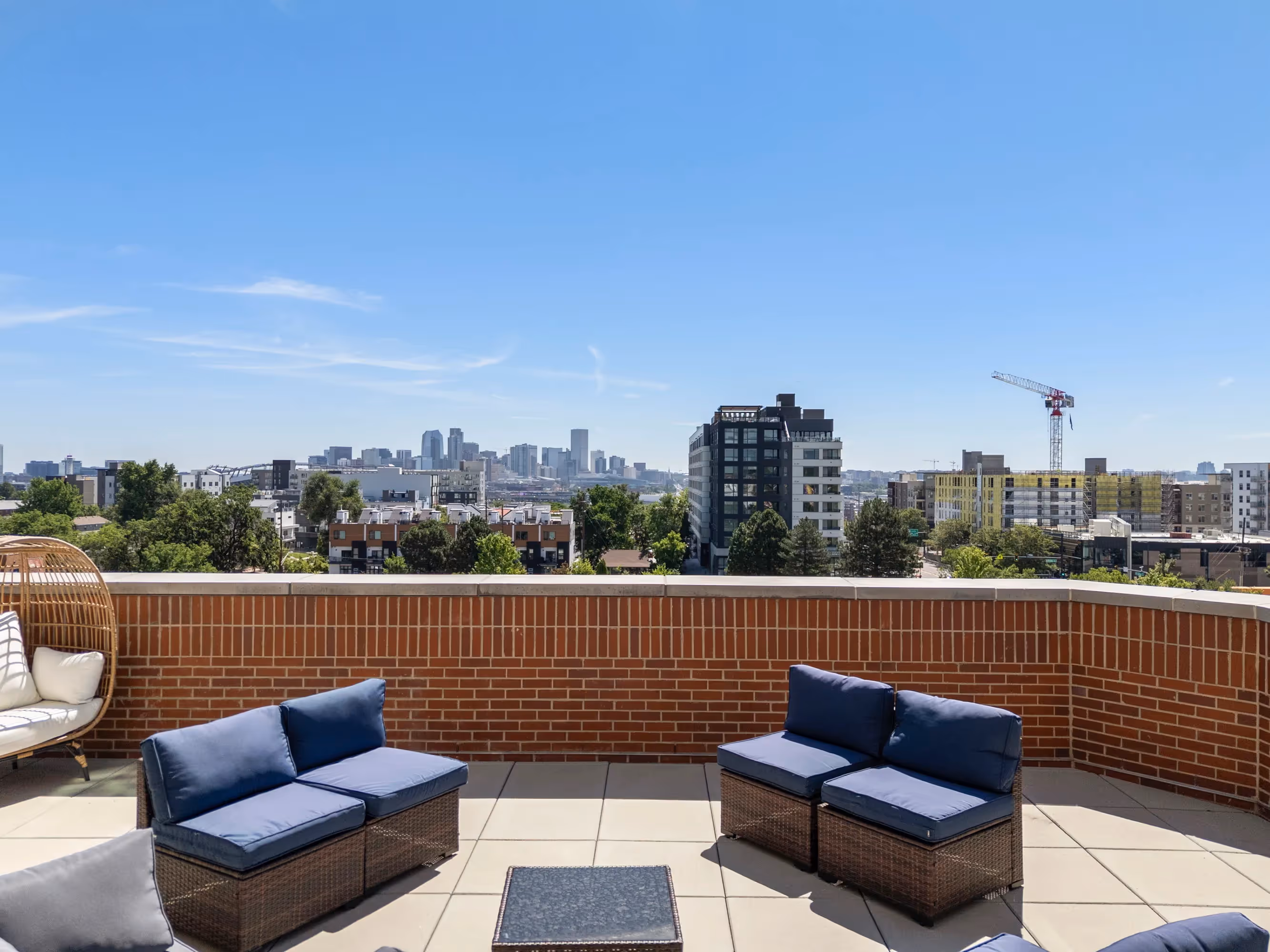 View of the common outdoor terrace at The Julian apartments in Sloans Lake, Denver, offering residents a lounge area with stunning city lights and evening sky.