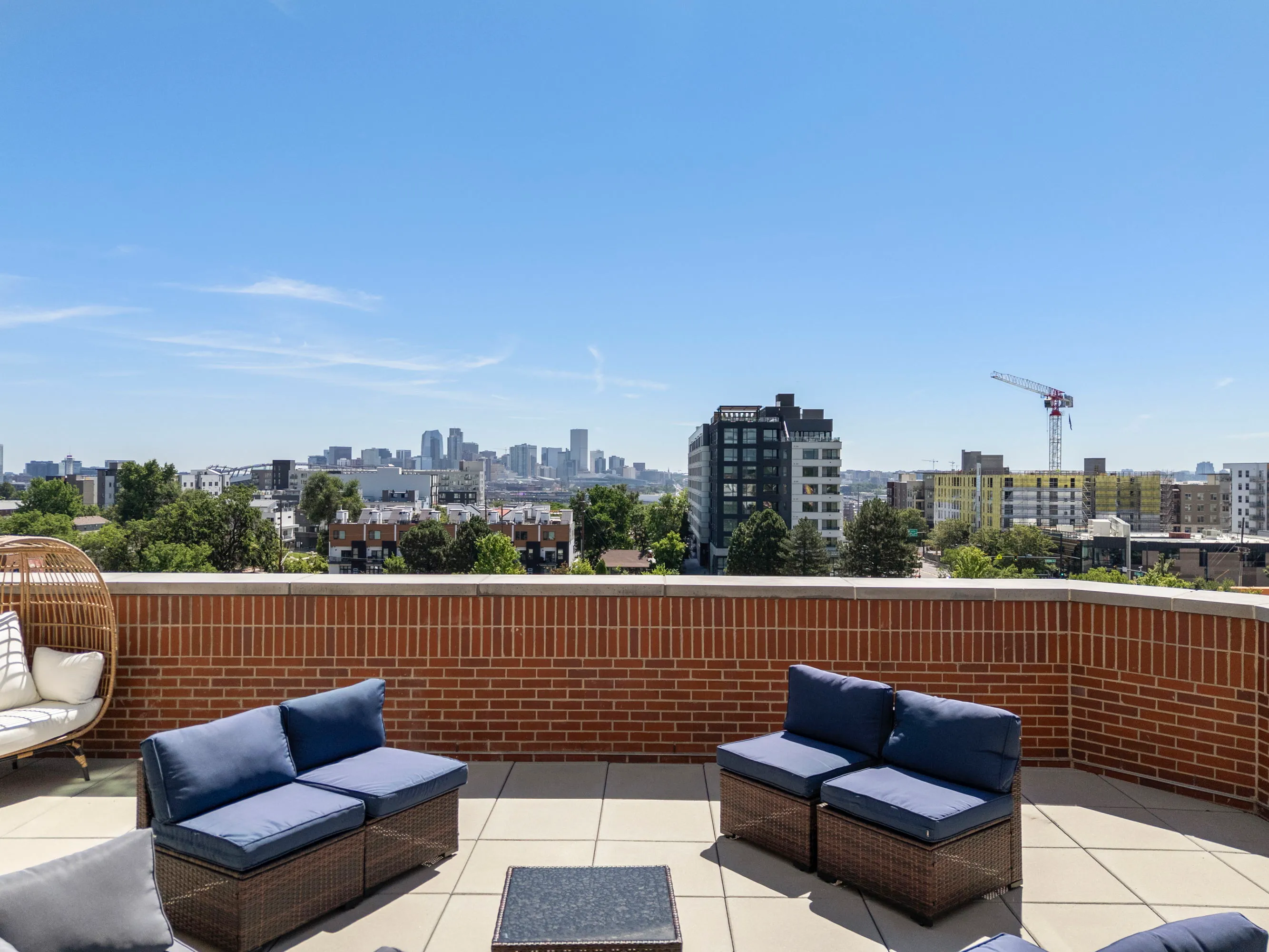 View of the common outdoor terrace at The Julian apartments in Sloans Lake, Denver, offering residents a lounge area with stunning city lights and evening sky.