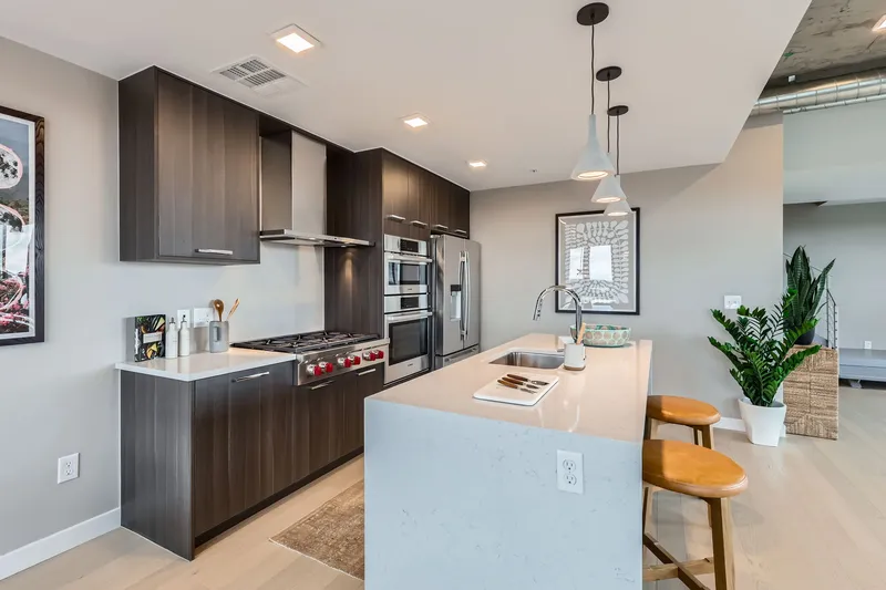 Contemporary kitchen in a luxury apartment at The Julian in Sloans Lake, Denver, showcasing a large island, gas range, and stainless steel appliances.