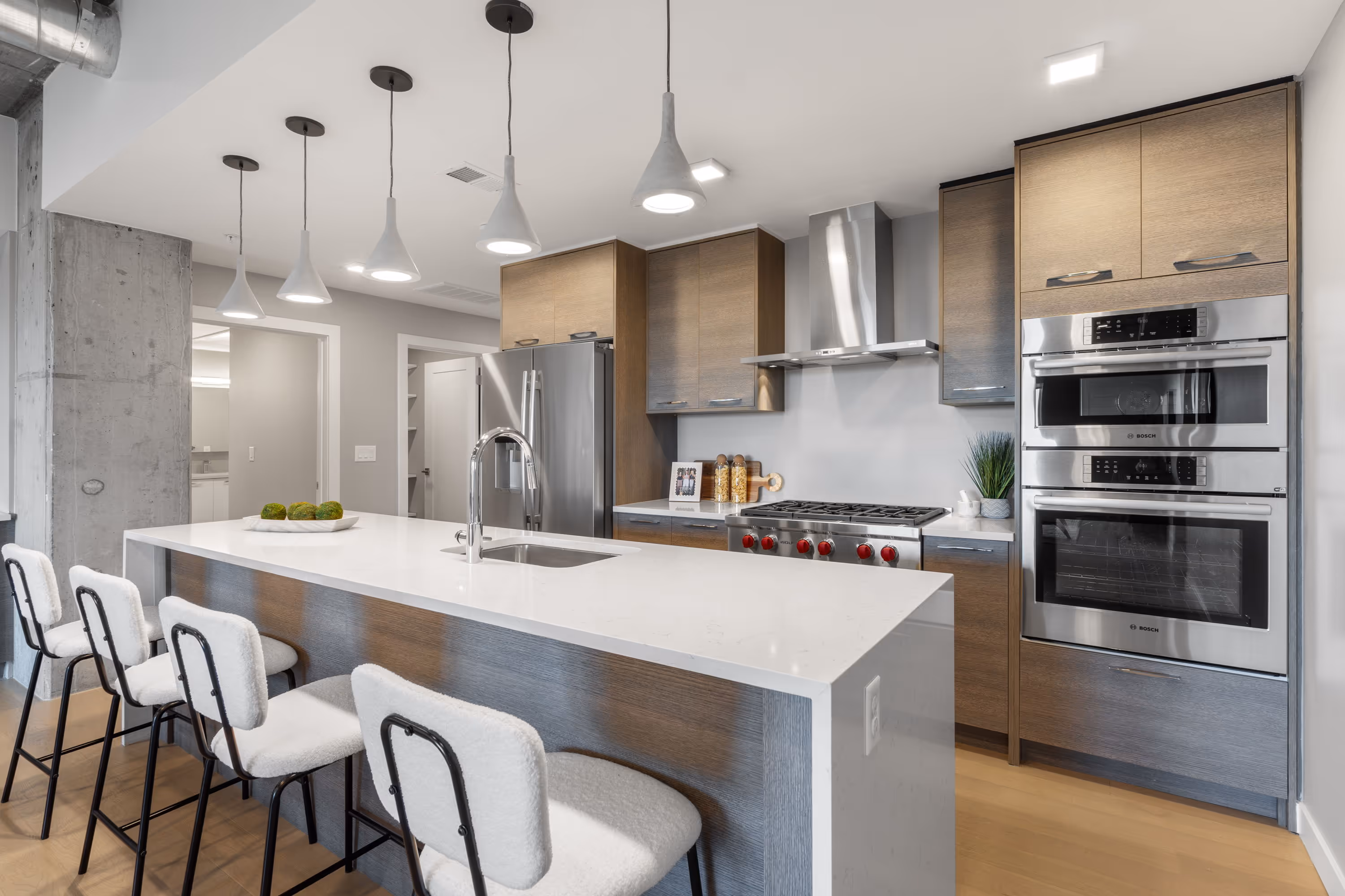 Gourmet kitchen in a luxury apartment at The Julian in Sloans Lake, Denver, featuring dark wood cabinetry, stainless steel appliances, and a large island.