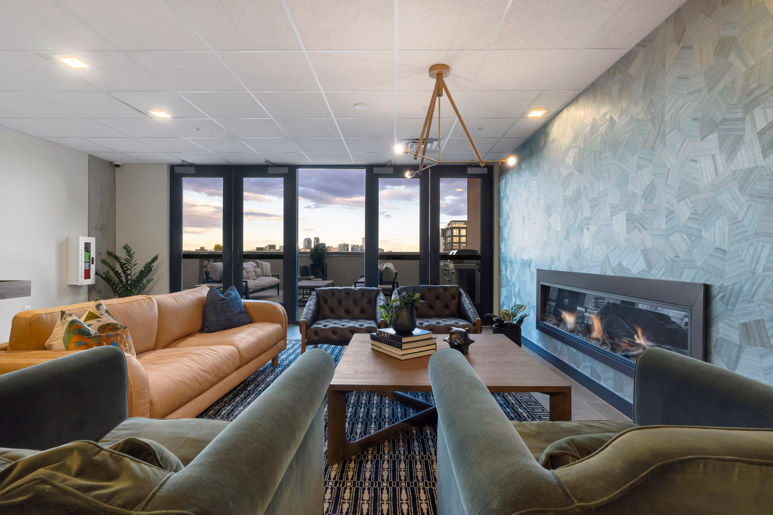 View of the common outdoor terrace at The Julian apartments in Sloans Lake, Denver, offering residents a lounge area with stunning city lights and evening sky.