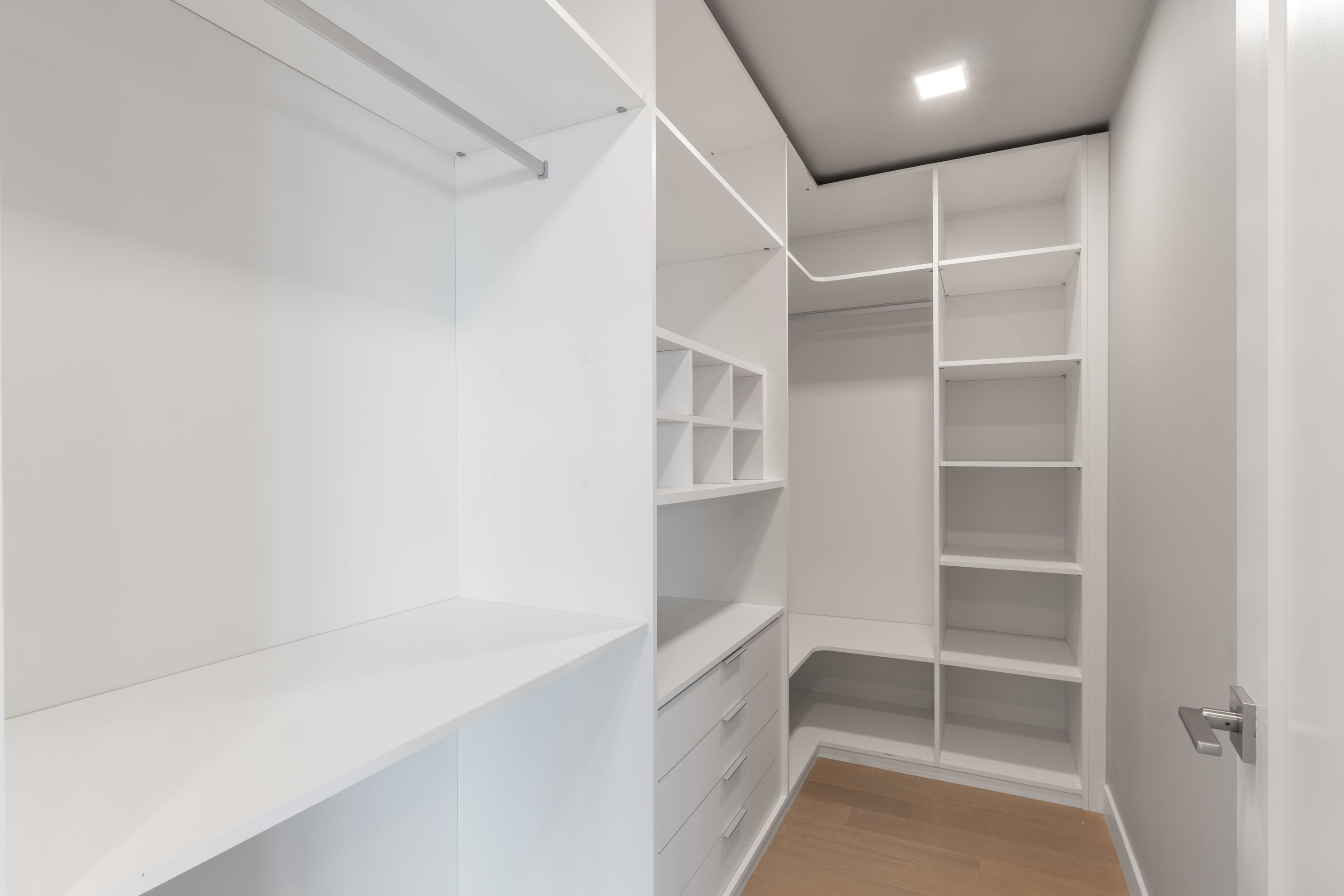 Spacious walk-in closet with custom white shelving and built-in drawers in a luxury apartment at The Julian in Sloans Lake, Denver.