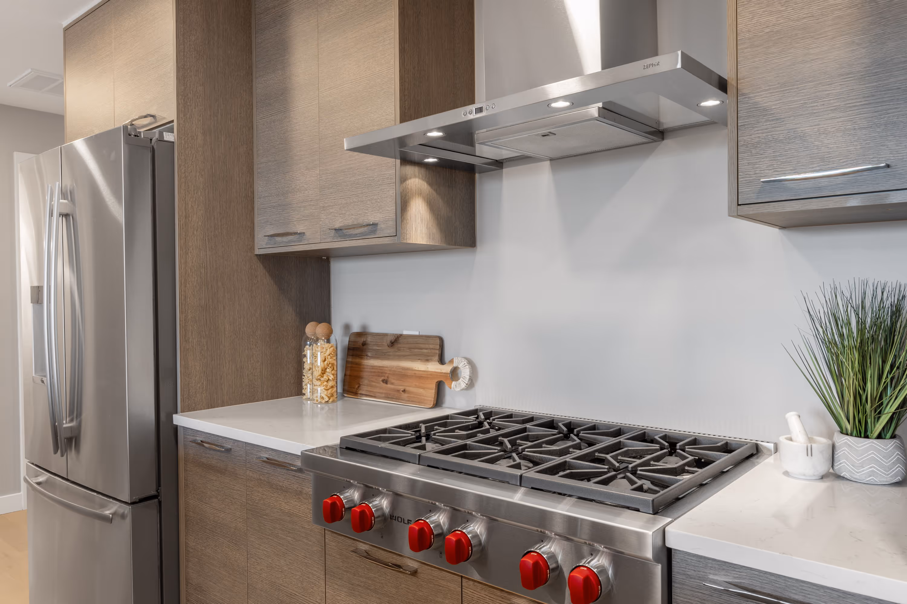 Gourmet kitchen in a penthouse apartment at The Julian in Sloans Lake, Denver, featuring a large island, gas range, double ovens, and dark wood cabinetry.