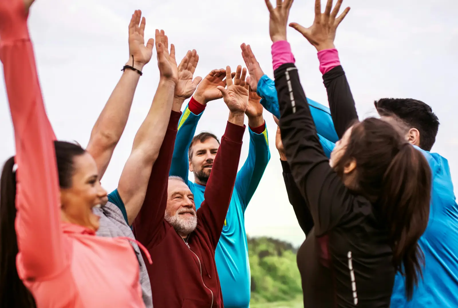 Grupa ludzi skacze z rękoma w górze w geście zwycięstwa.
