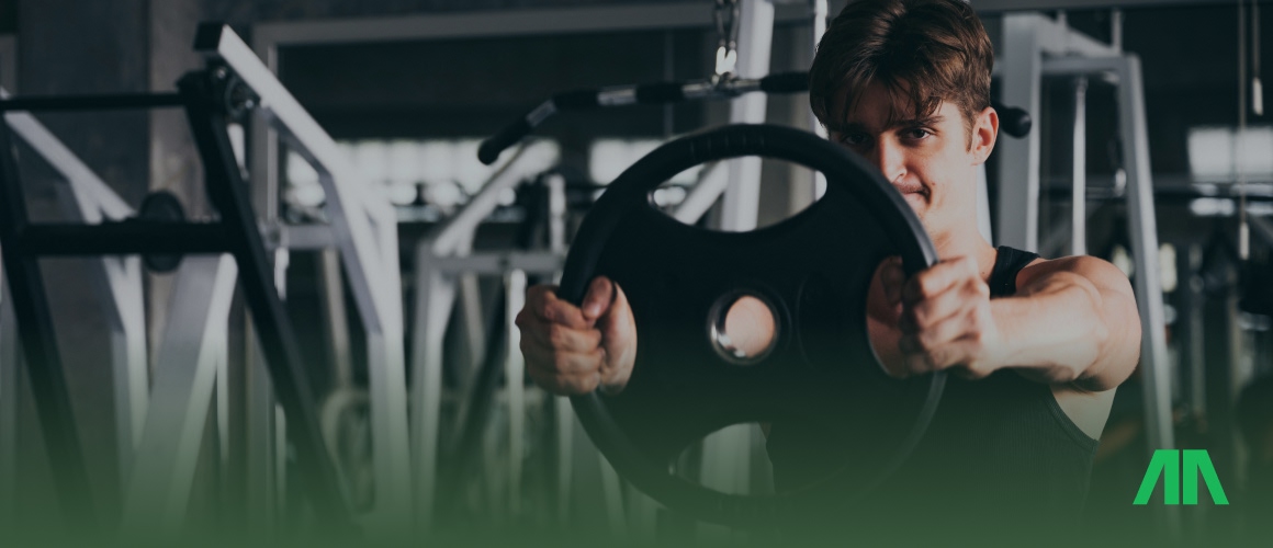 Trener personalny pokazuje na tablecie dane dotyczące postępów treningowych.