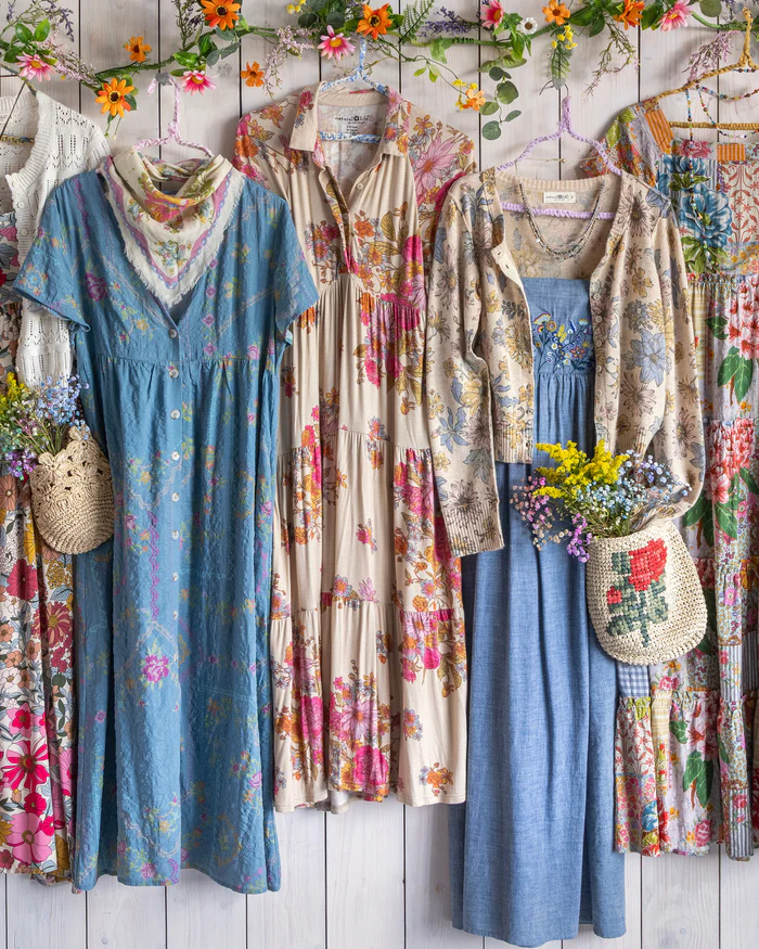 several colorful natural fiber dresses hanging on a wall