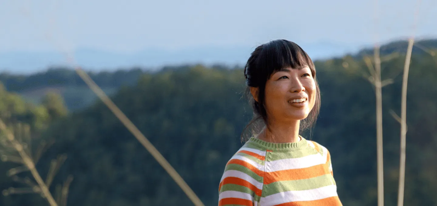 An Asian lady smiling while staring at a point far from the camera