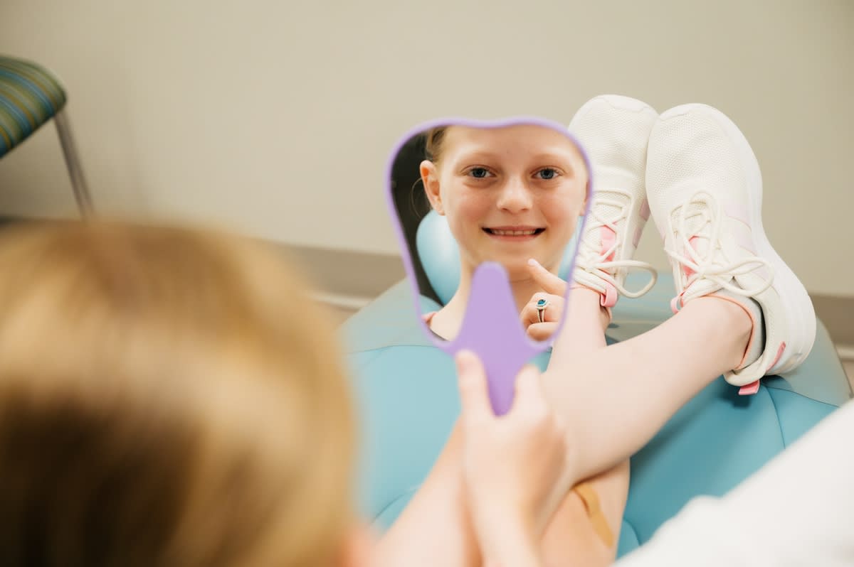 Pediatric dentist showing child a tooth model during examination at Issaqueena Pediatric Dentistry.