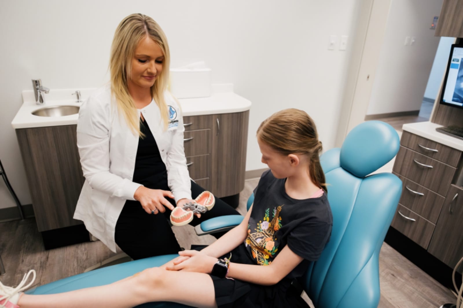 Dentist in white coat preparing a child patient for dental examination in treatment room