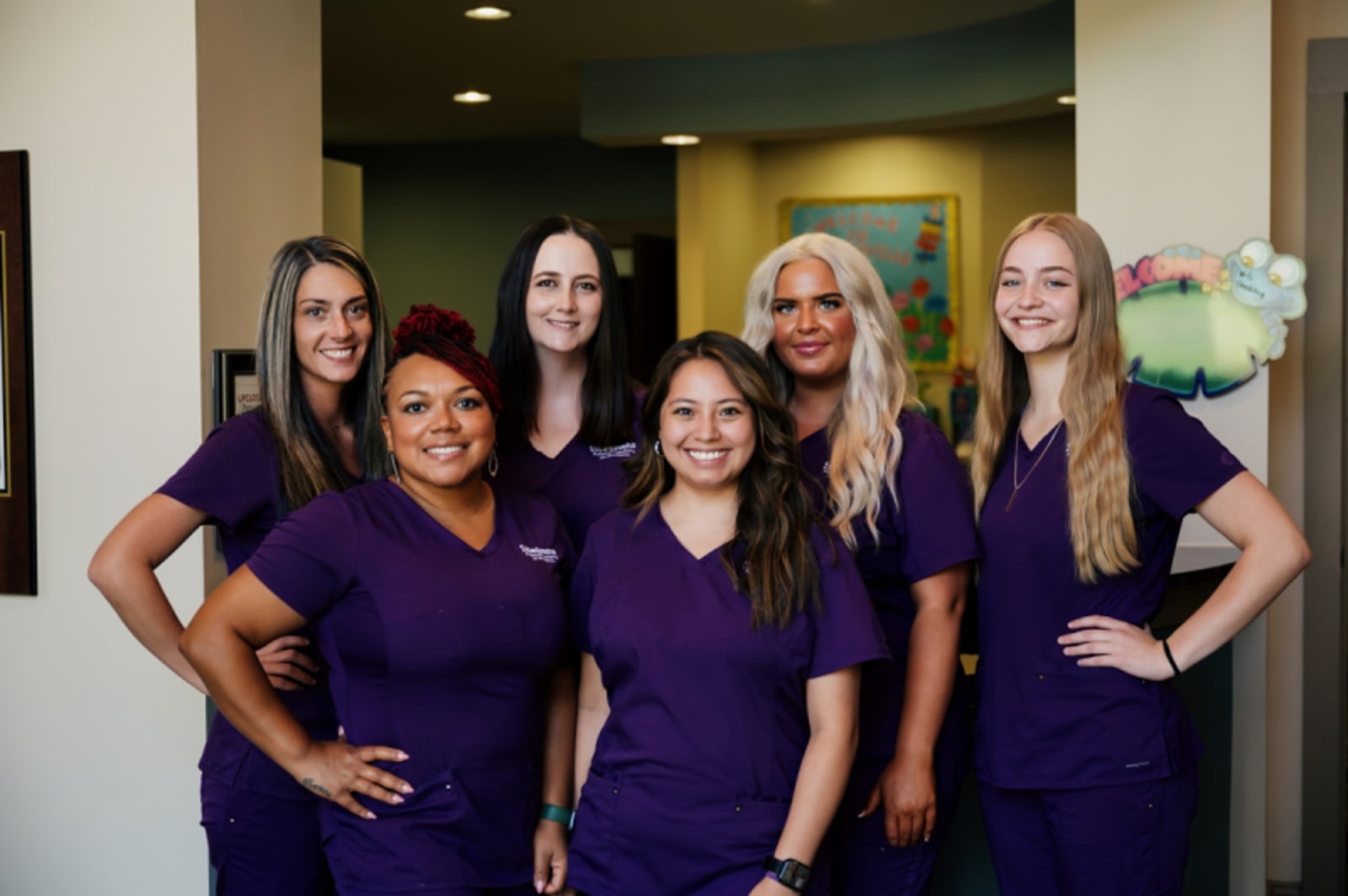 Team of dental professionals in purple scrubs standing together at Issaqueena Pediatric Dentistry Seneca location