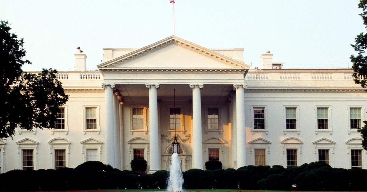 The White House North Portico in Washington, D.C., with a fountain and flower beds in the foreground.