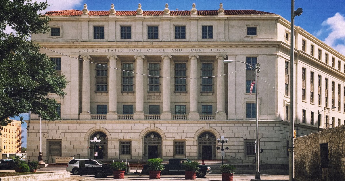 Exterior of a U.S. federal courthouse building with classical stone columns and an American flag.