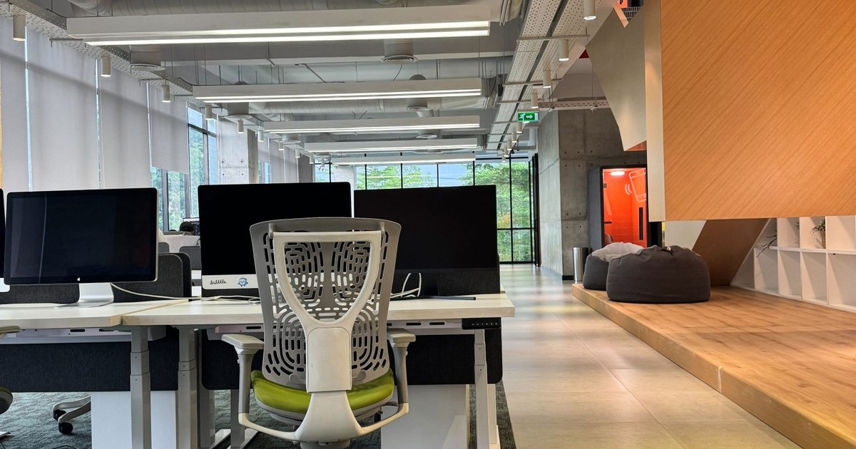 Rows of empty desks in a modern open-plan office, evoking the wave of AI layoffs moving through white-collar workplaces in 2026.