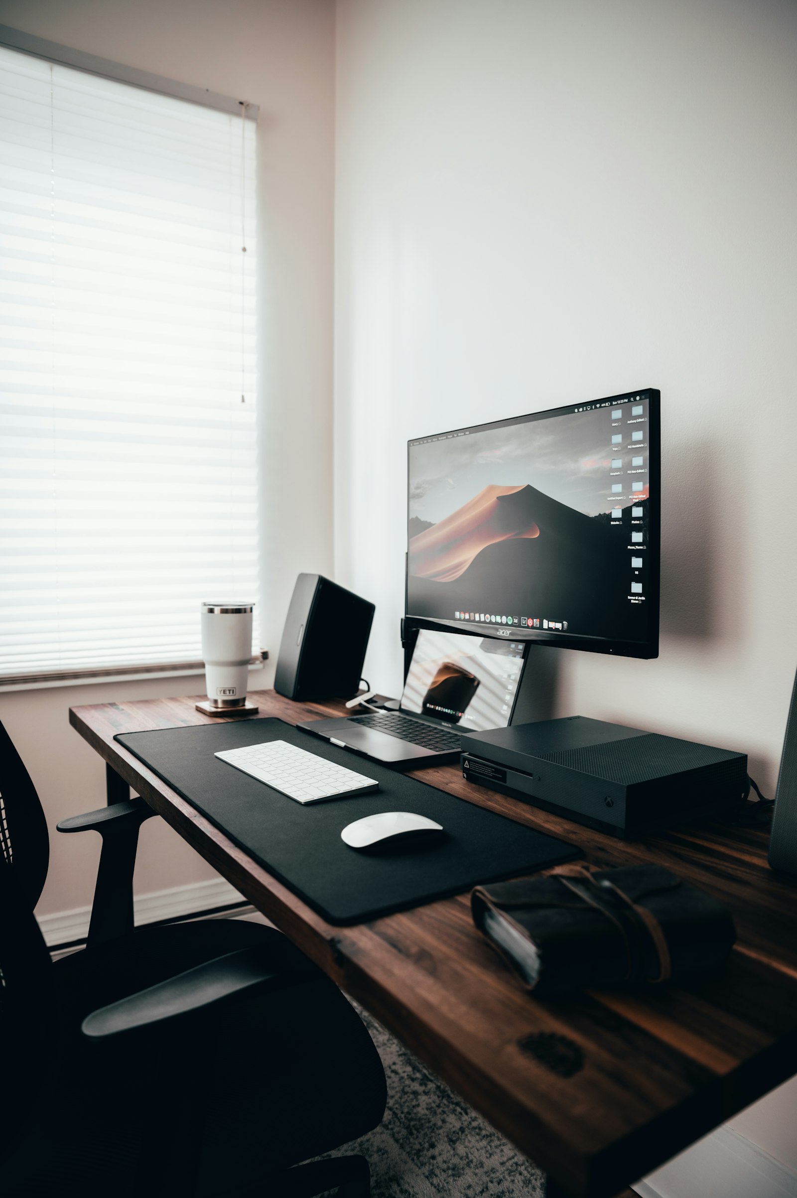 An unattended desk with a computer running on its own beside a window, evoking an AI agent working without a person at the keyboard