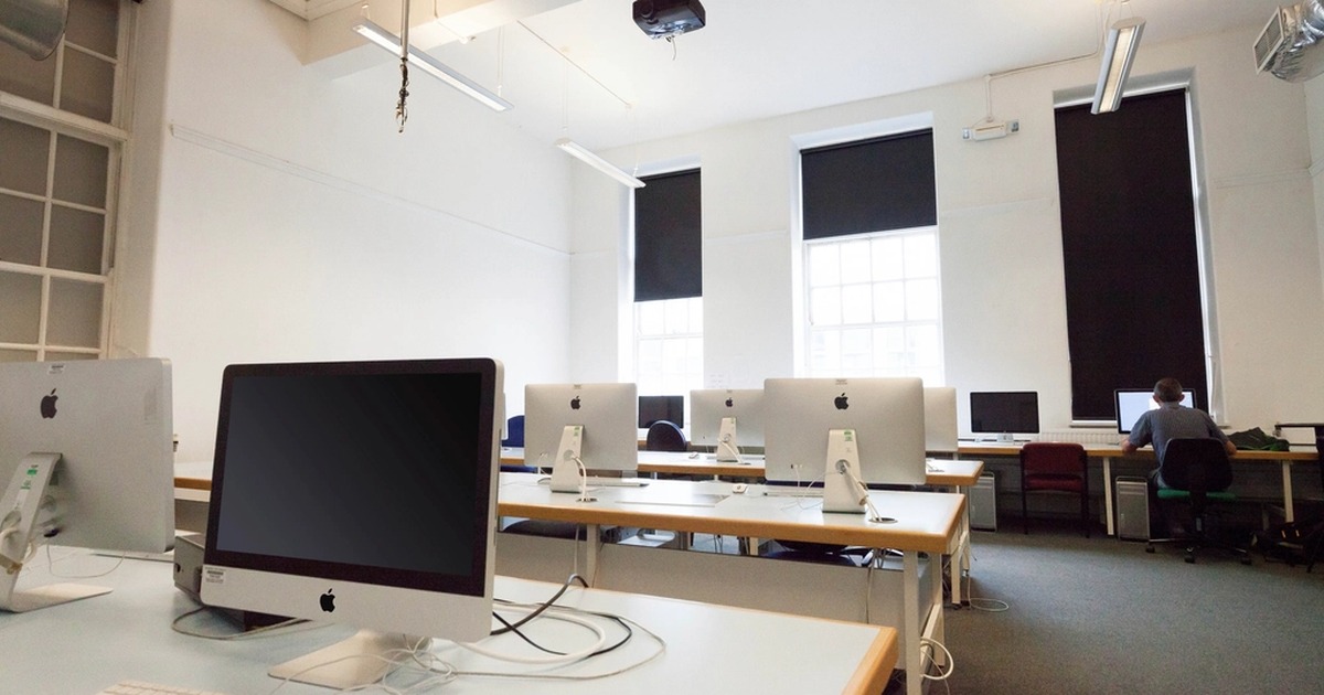 A modern school computer lab with rows of desktop computers, illustrating AI literacy instruction in K-12 schools.