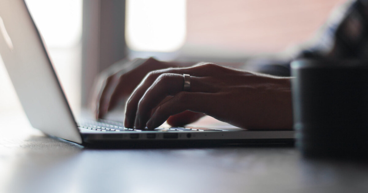 Close-up of hands typing on a laptop keyboard, representing the AI tools now covered by Florida's new K-12 school policy.