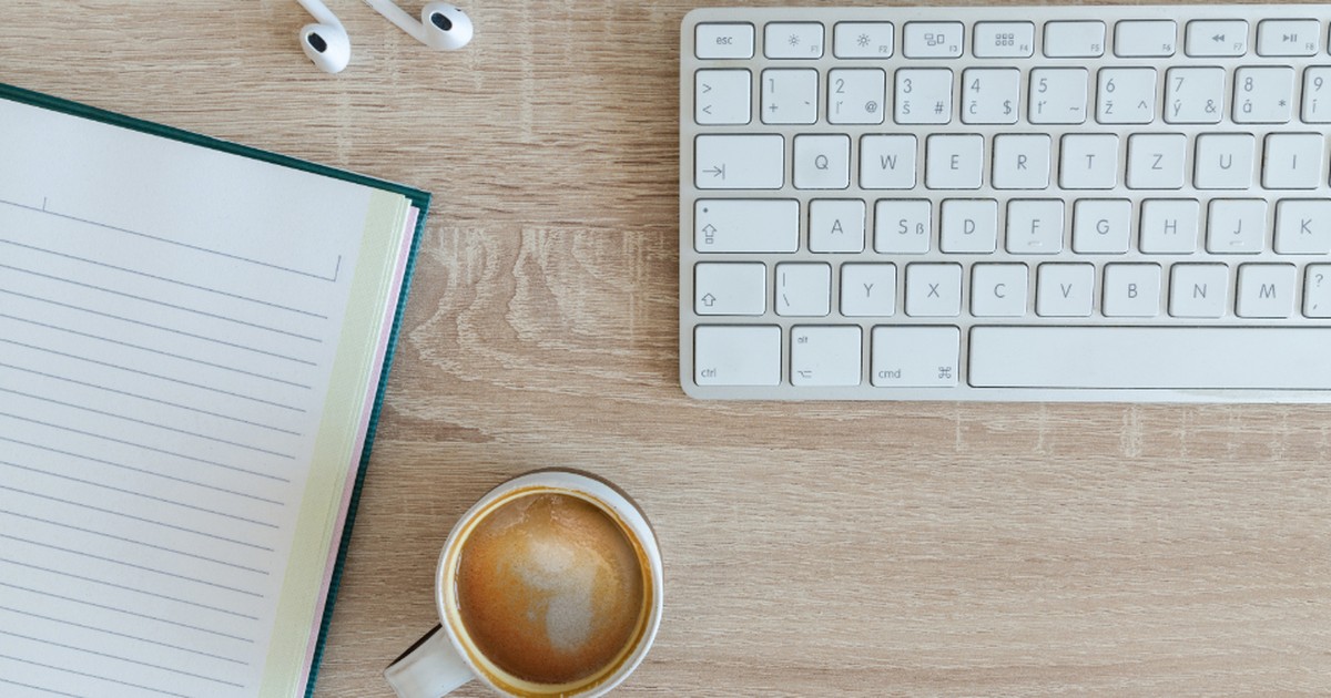 An overhead view of an empty desk with a keyboard, notebook, and coffee cup, evoking the empty seats left behind by 2026's wave of AI job cuts.