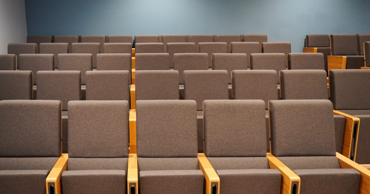 Rows of empty seats in a modern lecture hall at a higher education institution.