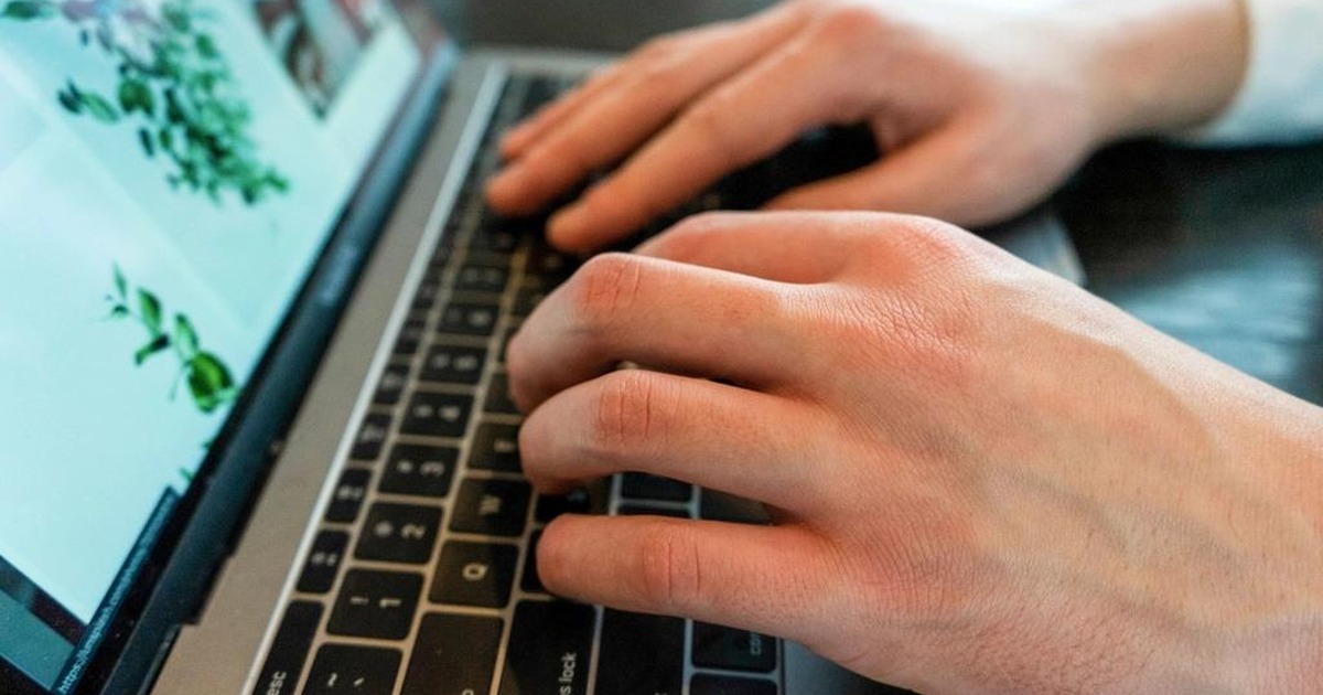 Close-up of two hands typing on a laptop keyboard, illustrating the rise in AI use at work found in PwC's 2026 Global Workforce Survey.