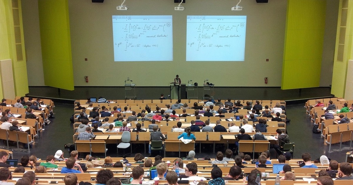 Overhead view of a packed university lecture hall during a class, illustrating higher education governance and oversight.