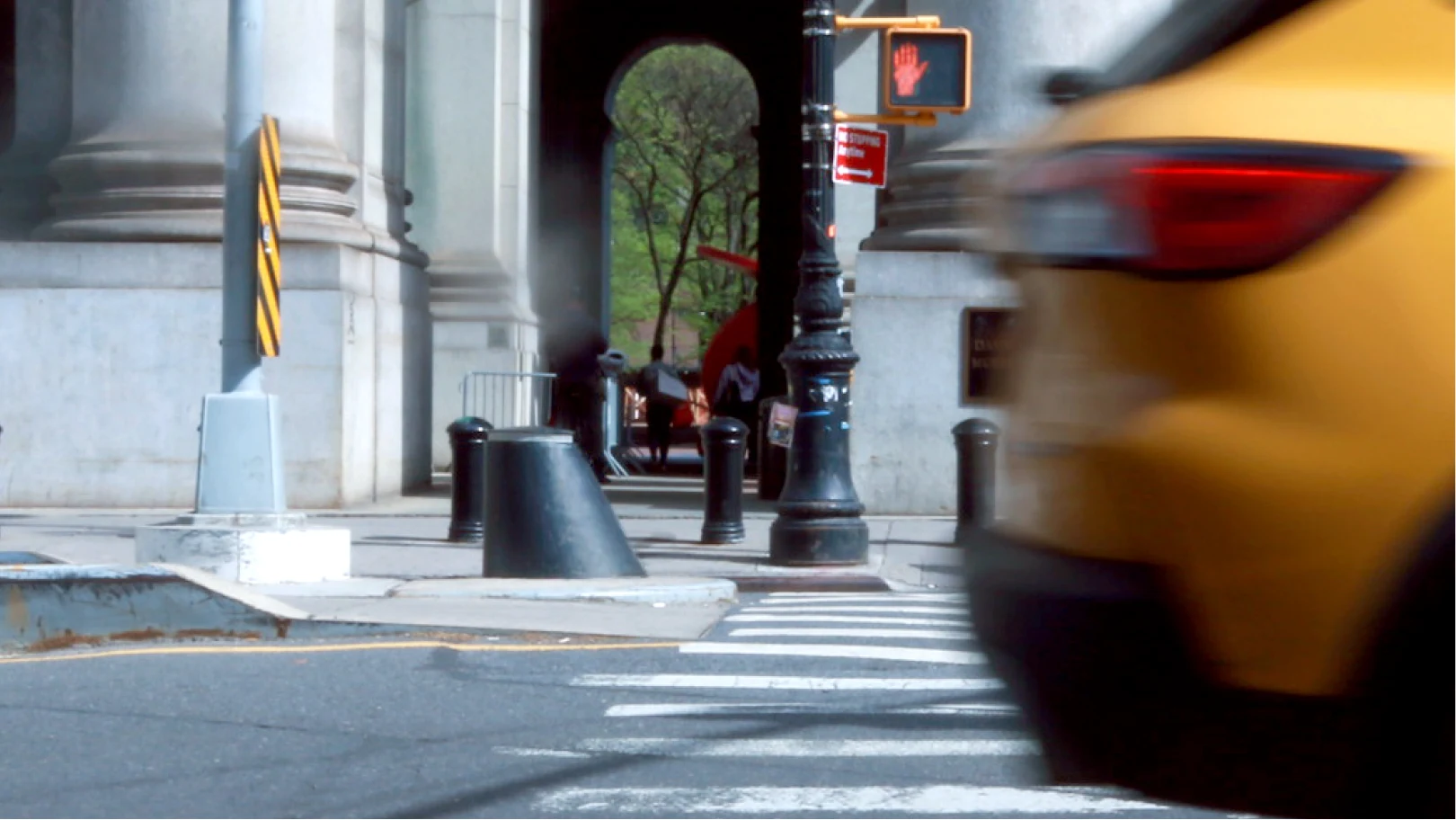 Yellow cab passing a cone bollard outside the David N. Dinkins Municipal Building