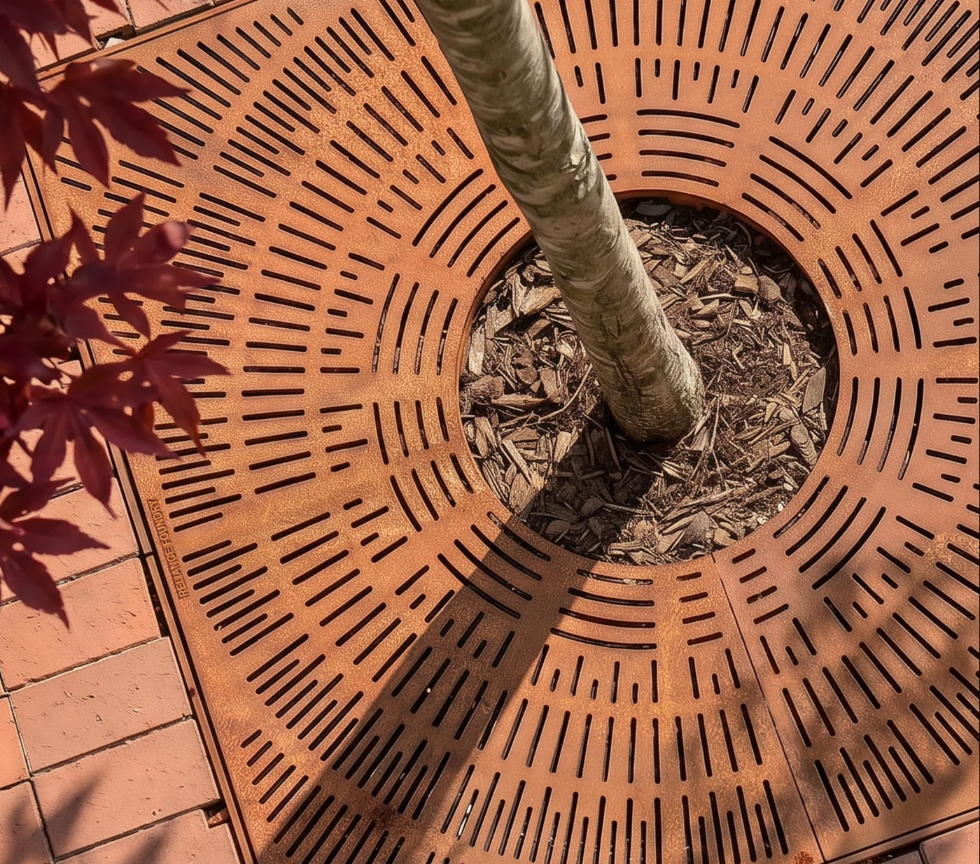 Tree grate under a red maple on brick paving