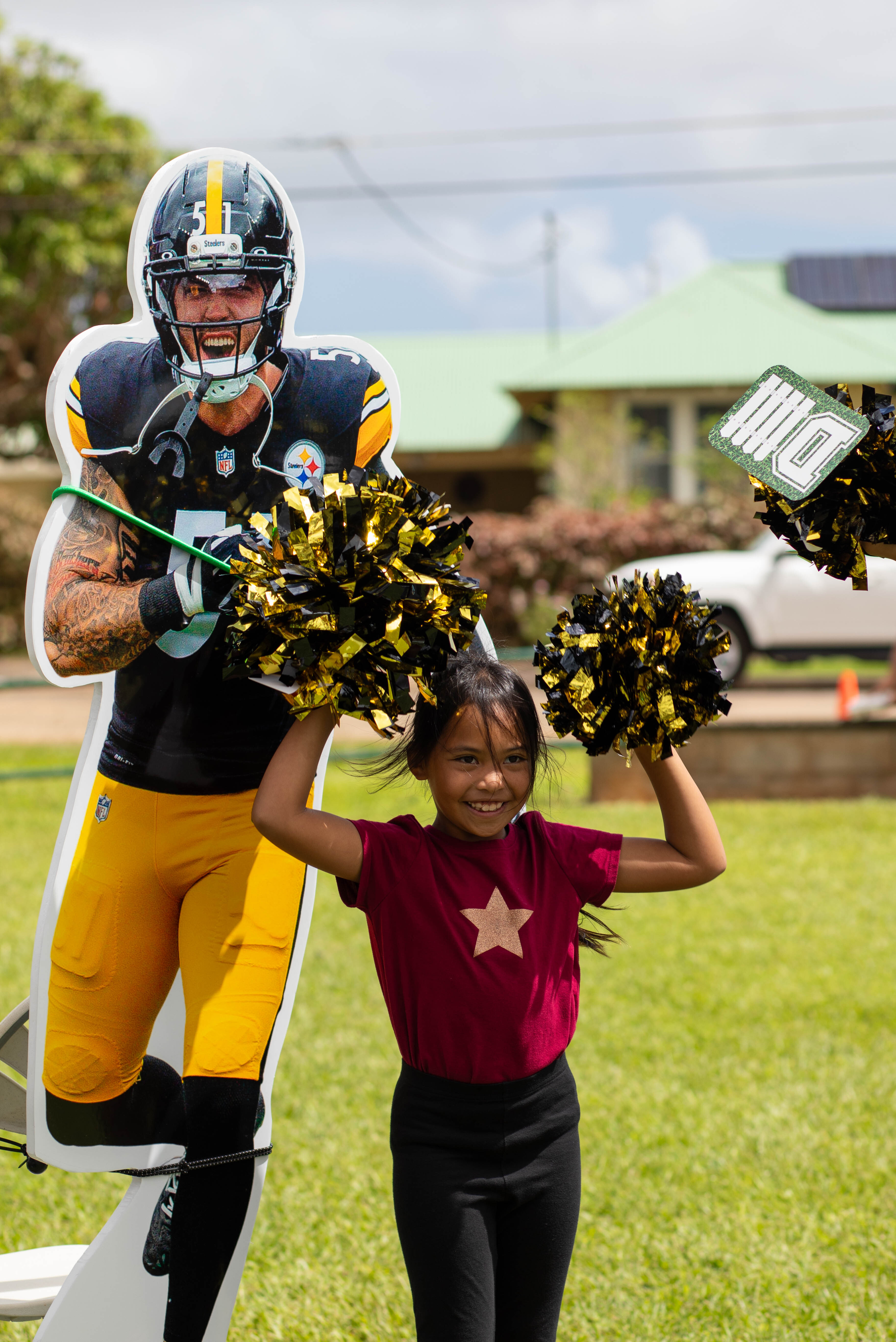 A girl cheers with pom-poms next to a Nick Herbig Steelers cutout