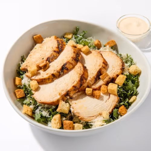 Grilled chicken kale Caesar salad prepared for an employee lunch program