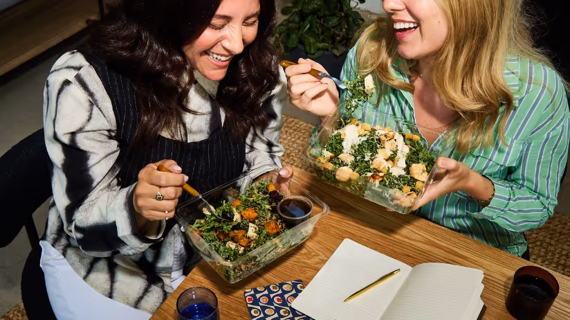 Two coworkers enjoying lunch together as part of an office meal program