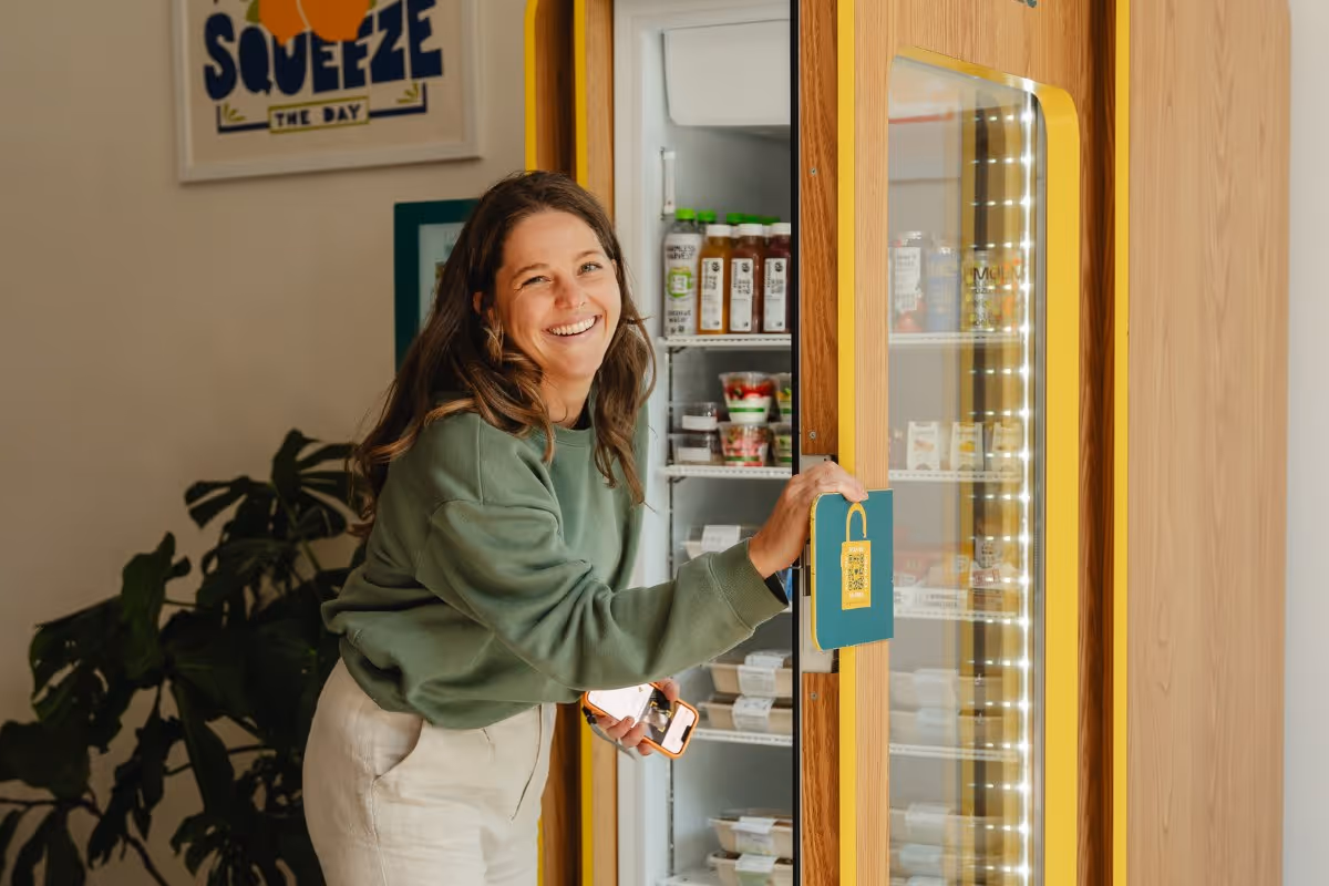 Woman selecting a chef-made meal from a CookUnity Smart Fridge in the workplace