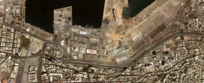 Aerial view of an urban coastal area with dense buildings, a waterfront, and construction sites near the shore.