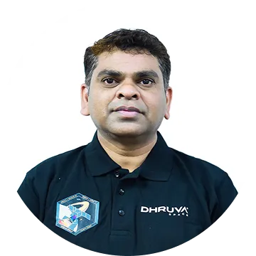 Portrait of a man wearing a black polo shirt with DHRUVA Space logo on the right chest and a space-themed patch on the left chest, against a white background.