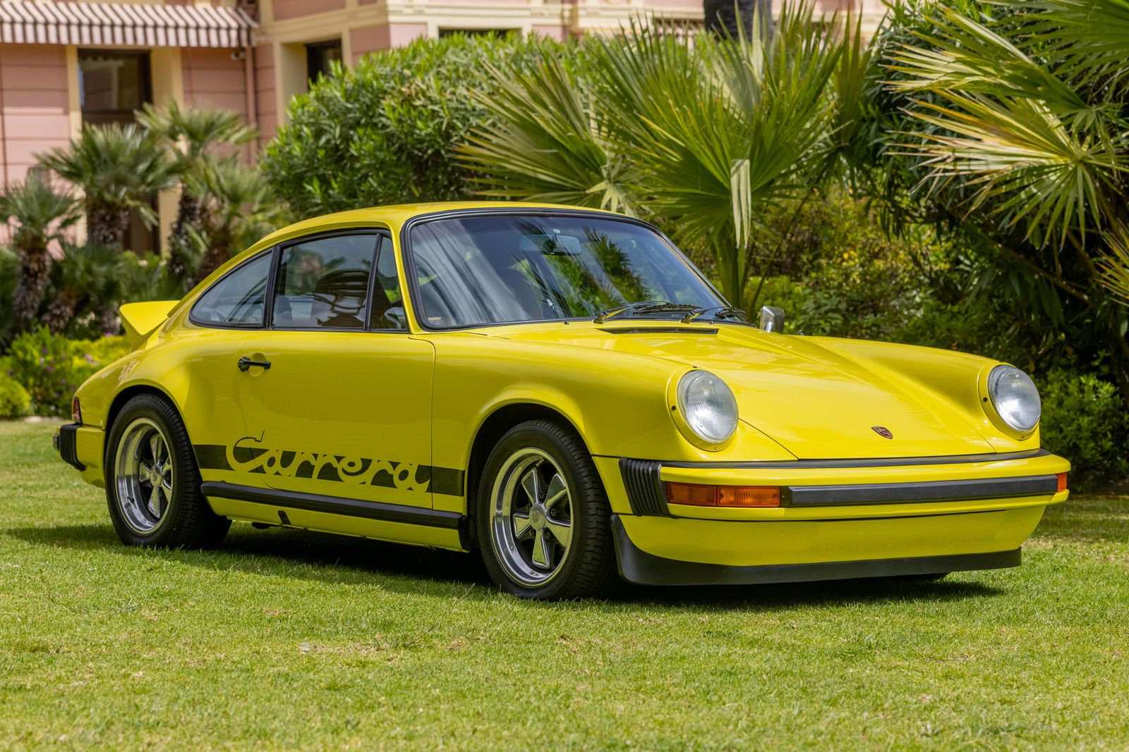 Porsche 911 Carrera jaune dans un jardin