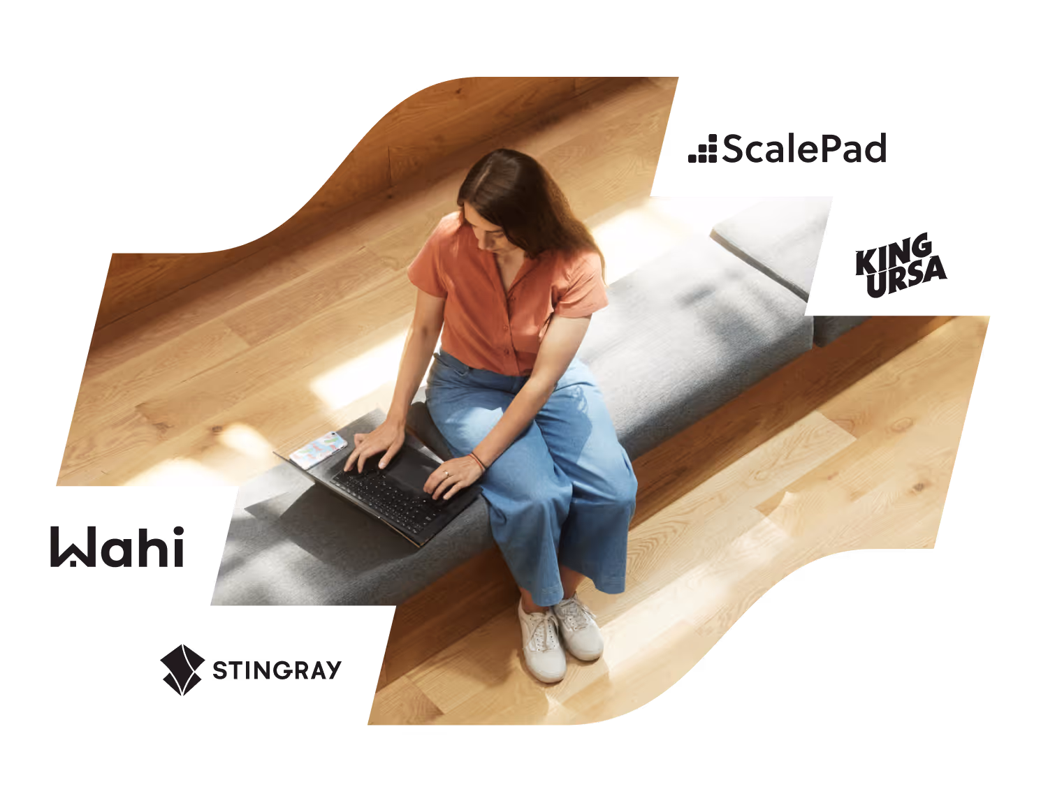 Woman with brown hair wearing an orange shirt and blue pants using a laptop while sitting on a gray bench.