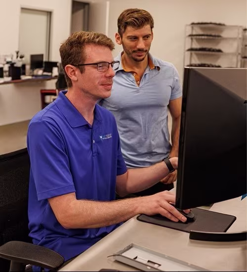 Two IT professionals reviewing data on a desktop computer monitor in a Rochester Hills managed services office
