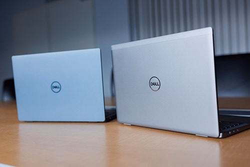 Two Dell laptops displayed side by side on a wooden desk, showcasing business IT hardware solutions for managed services