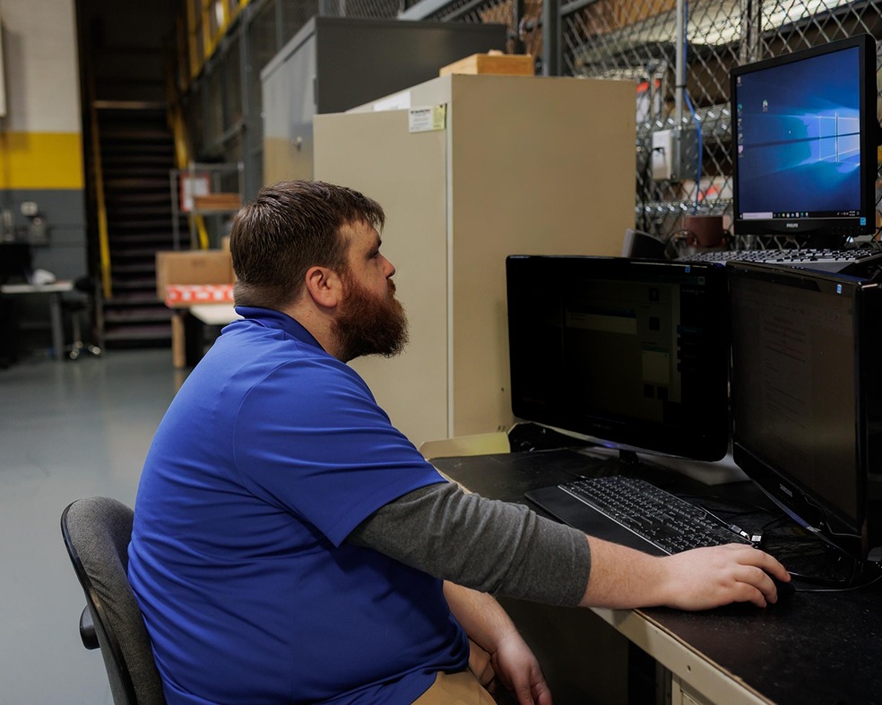 IT technician working at dual-monitor workstation in Rochester Hills managed services facility