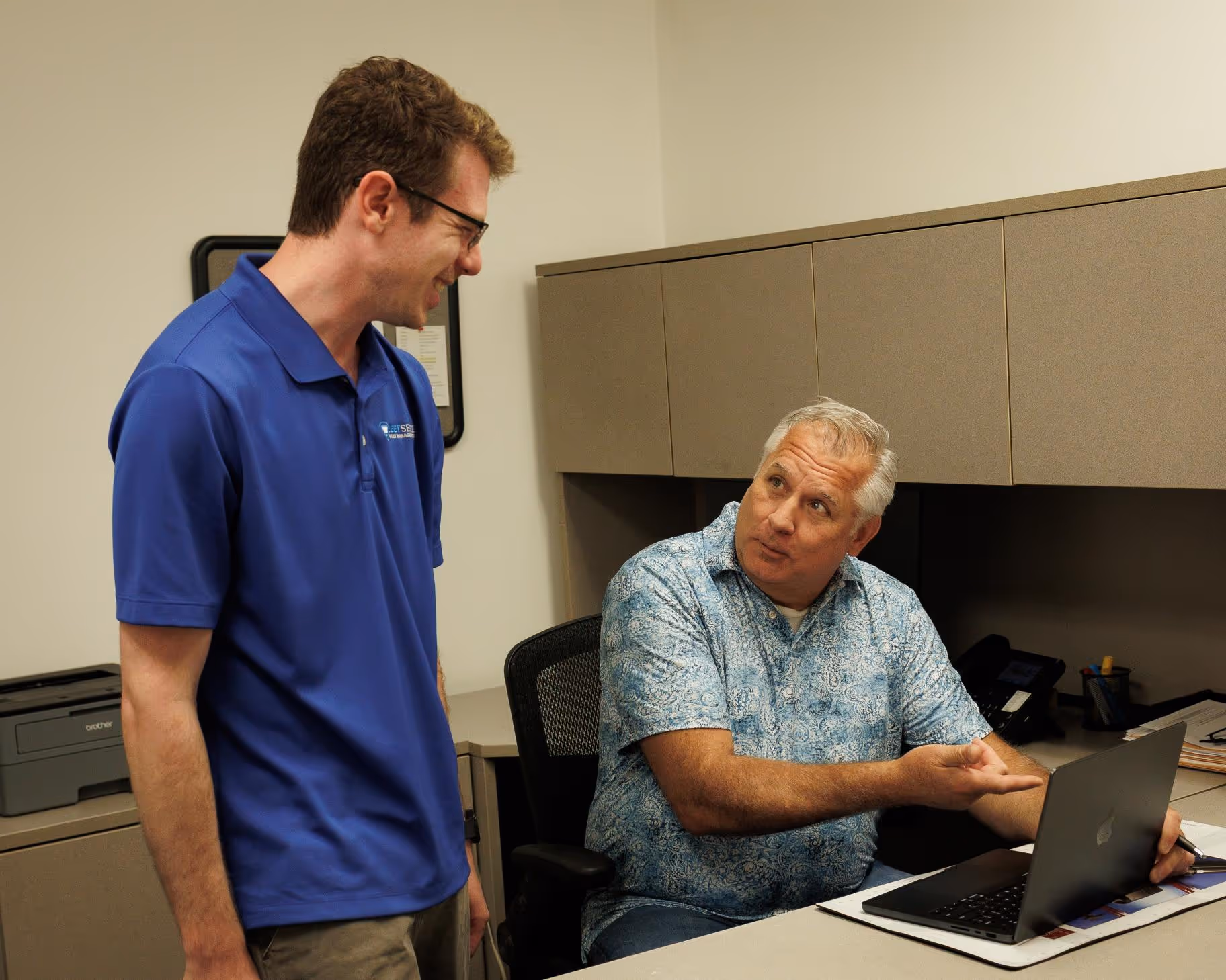 Leet IT technician discussing managed IT support solutions with a Rochester Hills business owner at office desk