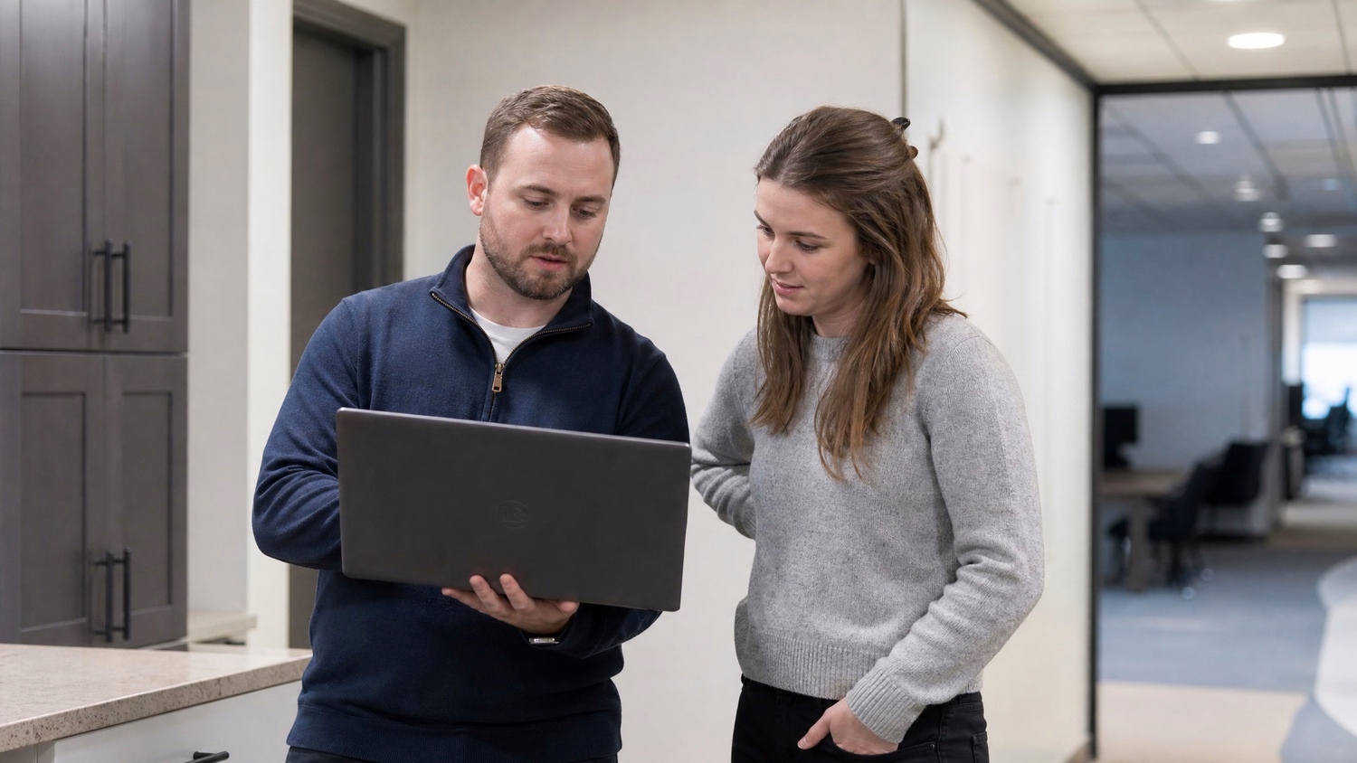INFORMAL HUDDLE An IT professional two people standing and talking near a ki