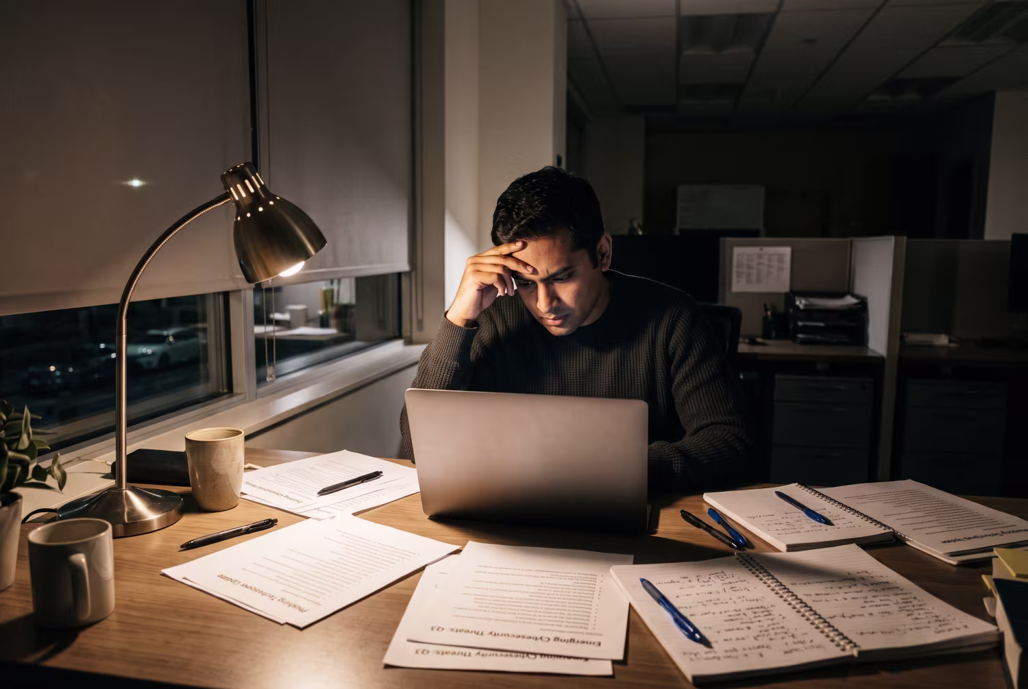 Cybersecurity team member reviewing security awareness training topics at dimly lit desk