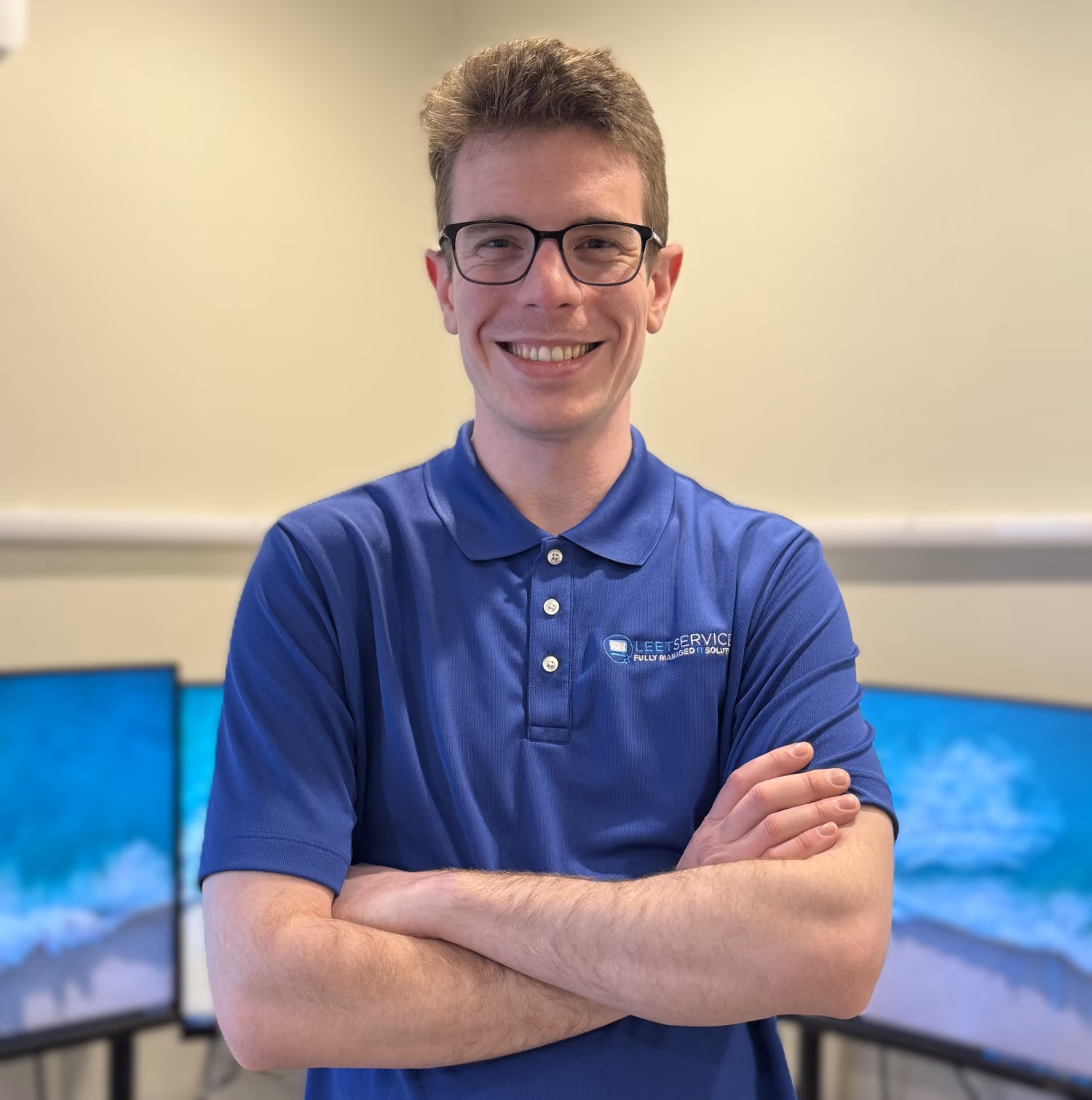 Jonathon Nash, Leet Services IT professional, smiling with arms crossed in front of computer monitors