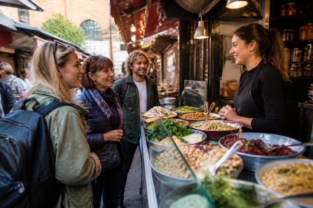 A group of friends enjoying fresh dishes at a Manchester vegetarian food tour market stall