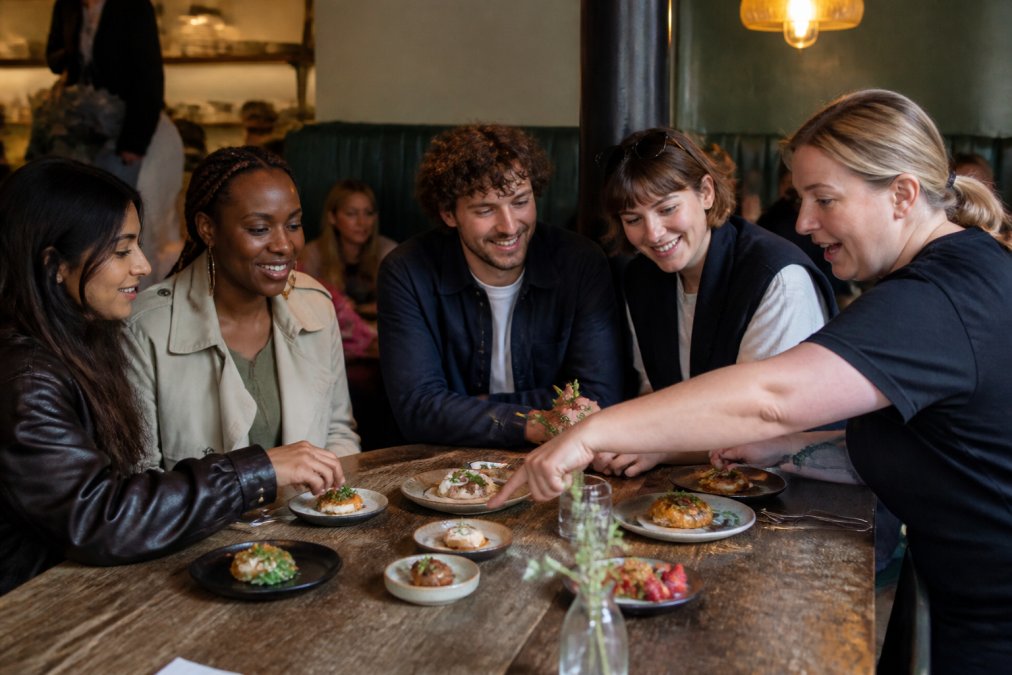 A guide explains local dishes to a group during a Manchester walking tour food tasting at a cozy eatery.