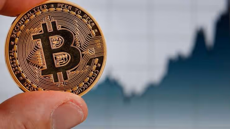um homem segurando uma moeda de bitcoin nova e brilhante