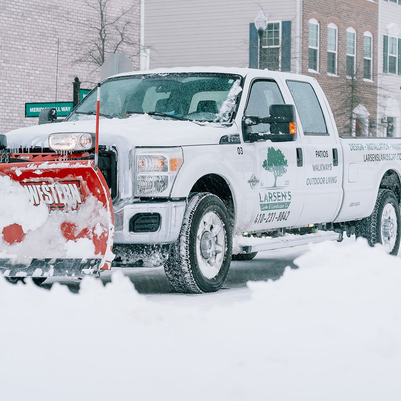 Larsen’s Lawn & Landscape vehicle with plow attachment clearing a road in Sunderland.