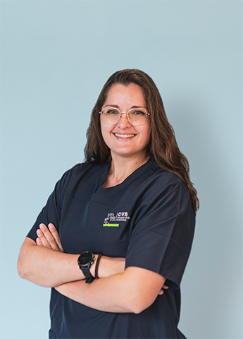 Smiling woman with glasses wearing a navy blue medical scrub against a light blue background.